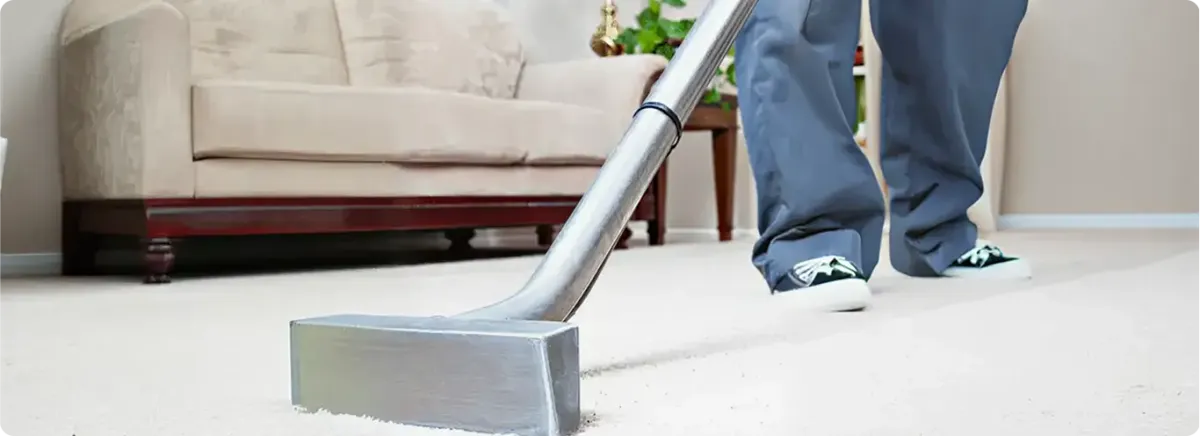 Carpet cleaning technician using a hot-water extraction wand on a light-colored carpet in a living room, Naperville, IL.